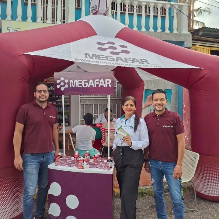 Equipo de Droguería Megafar en un evento comunitario, junto a su toldo de marca y productos en exhibición